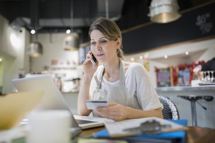 Business owner paying bills at laptop