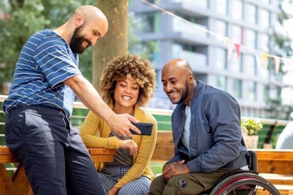 Social inclusion: three friends looking at the mobile phone