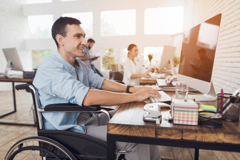 Man in a wheelchair works in a modern office, reflecting the support for employability, a key theme in the Telefónica Foundation Report.