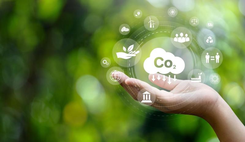 Person touches CO₂ icon in digital display, symbolizing ICT-enabled decarbonization and greenhouse gas reduction.