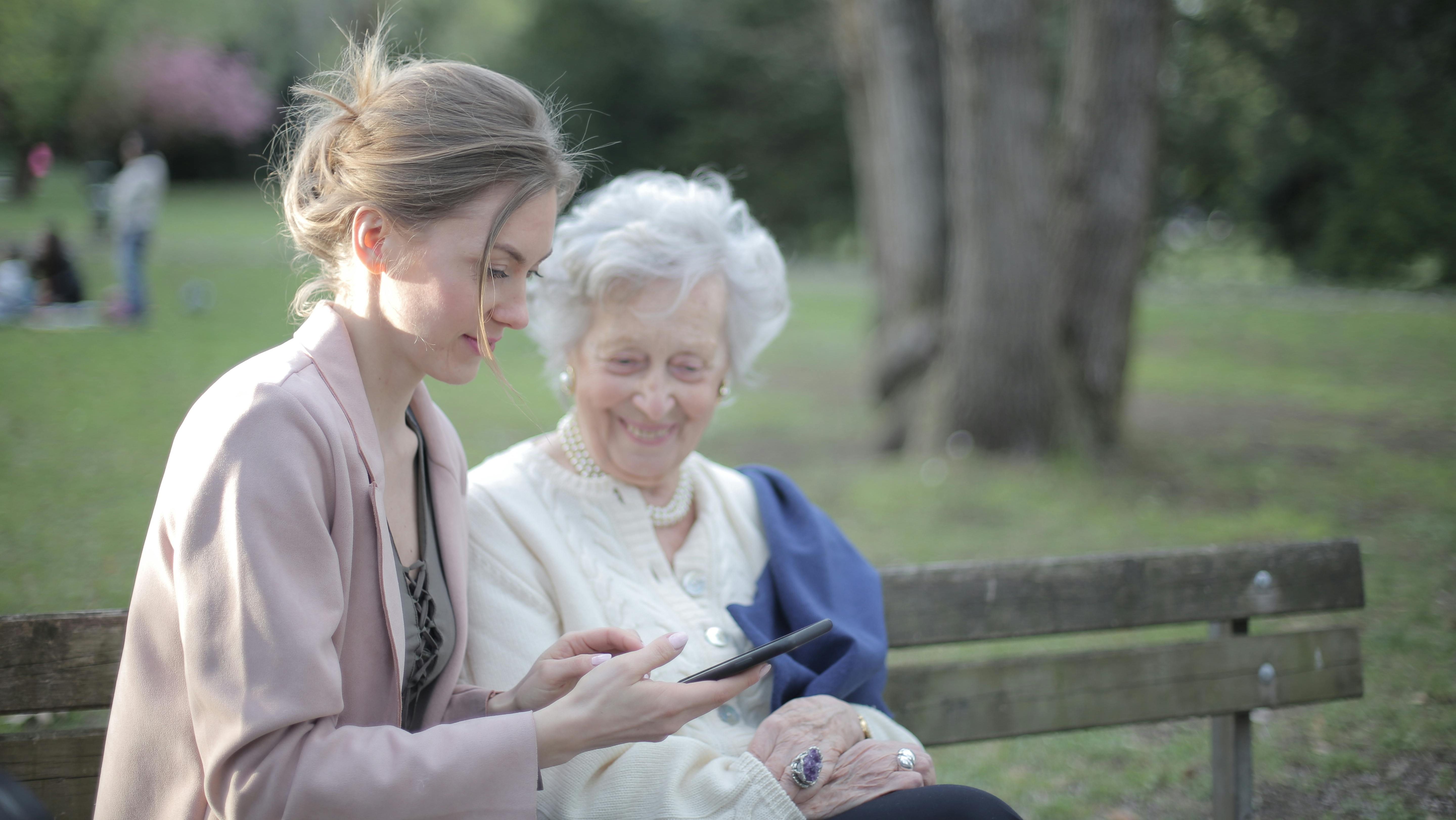 Older person using a tablet with assistance, illustrating the digital divide issue.