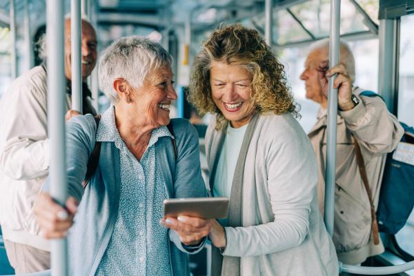 Two smiling people on public transport with a smartphone. The scene represents closeness, trust and accompaniment within the Principles of relationship with our customers at Telefónica.