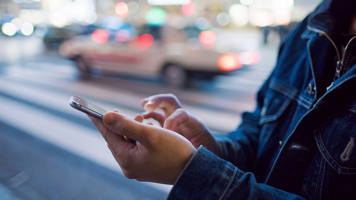 Hombre usando su smartphone al lado de una calle