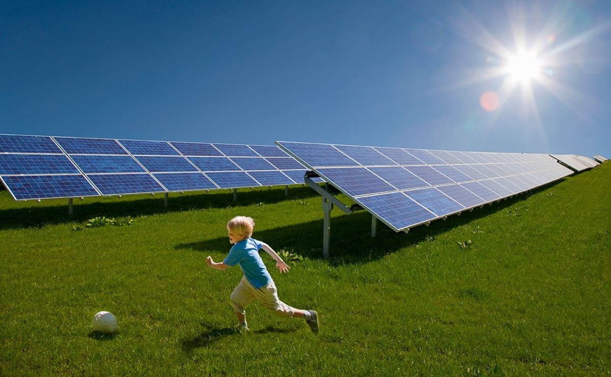 Niño jugando a la pelota cerca de paneles solares