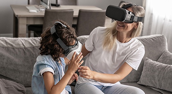 Mujer y niña utilizando gafas de realidad virtual en un sofá