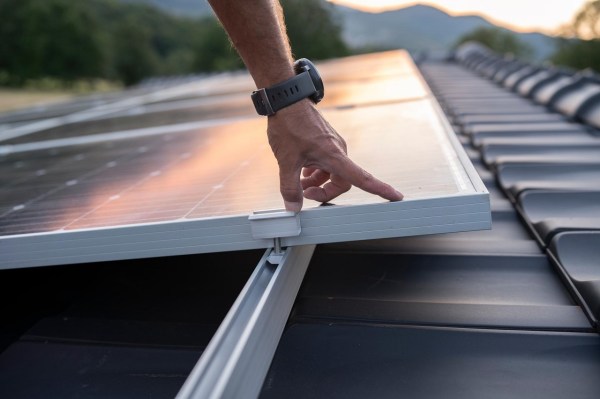 Un hombre tocando un panel -podría ser un panel solar- para mostrar la aportación de la tecnología al desarrollo sostenible (ODS).